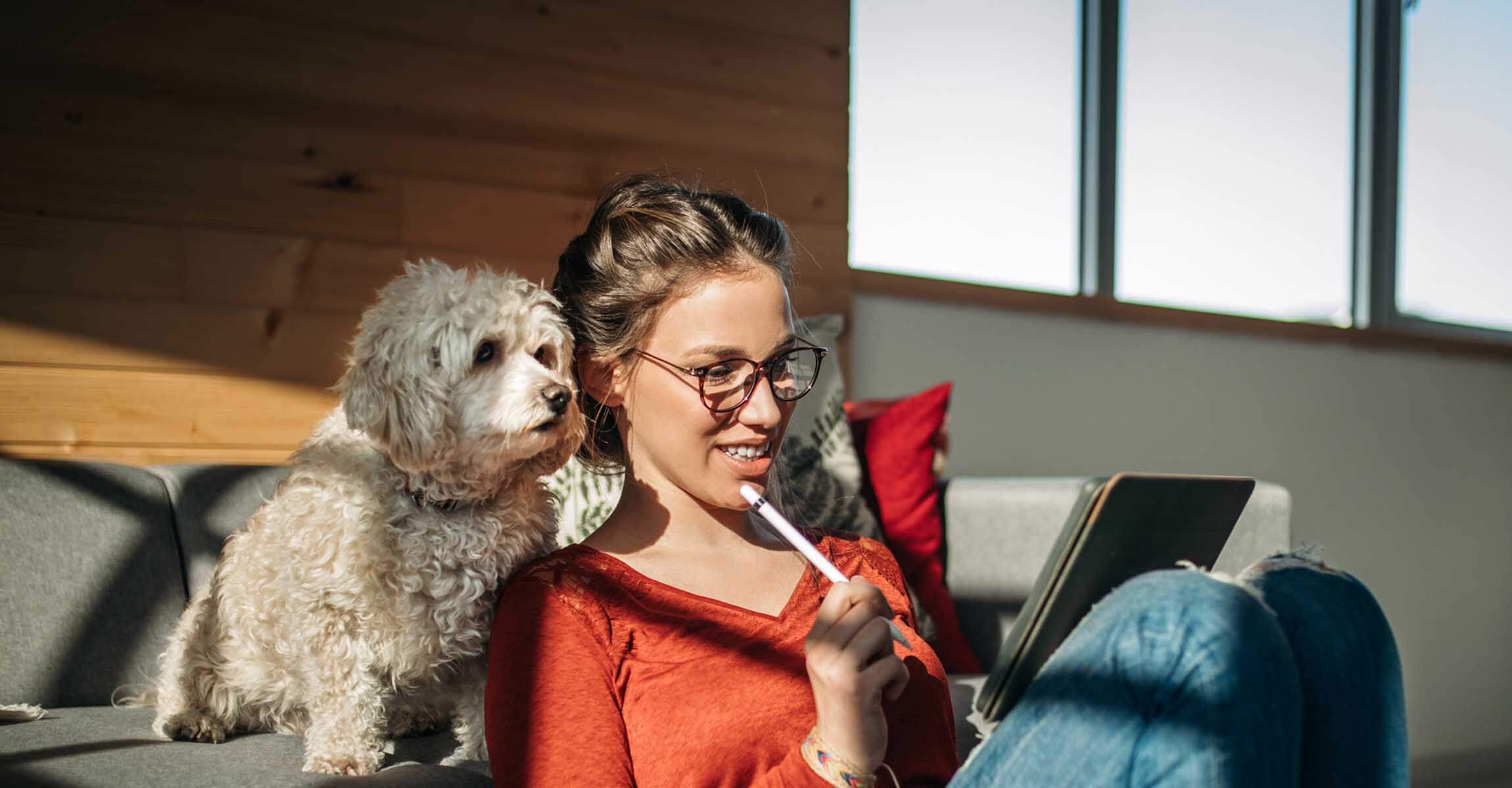 Woman in glasses and her dog looking at an iPad