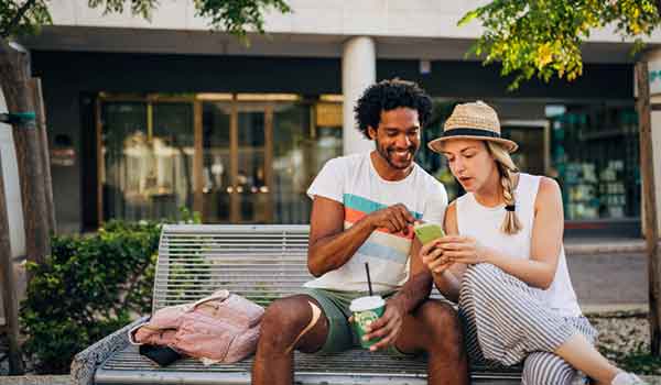 Young couple on bench looking at phone