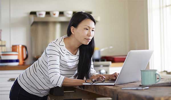 Woman looking at laptop in kitchen