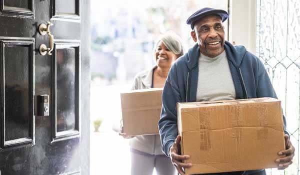 Older couple carrying boxes through a door