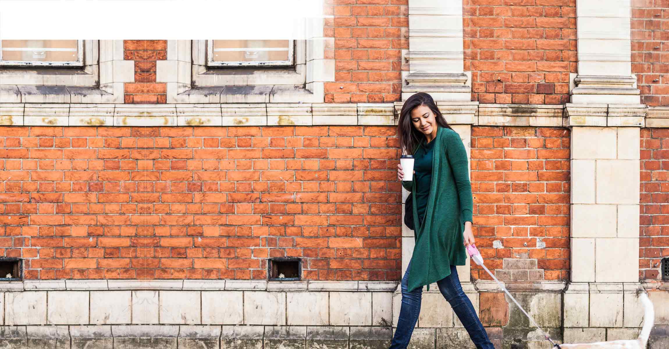 woman next to brick wall with coffee