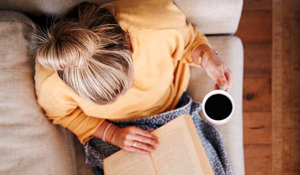 Woman sat on sofa drinking coffee