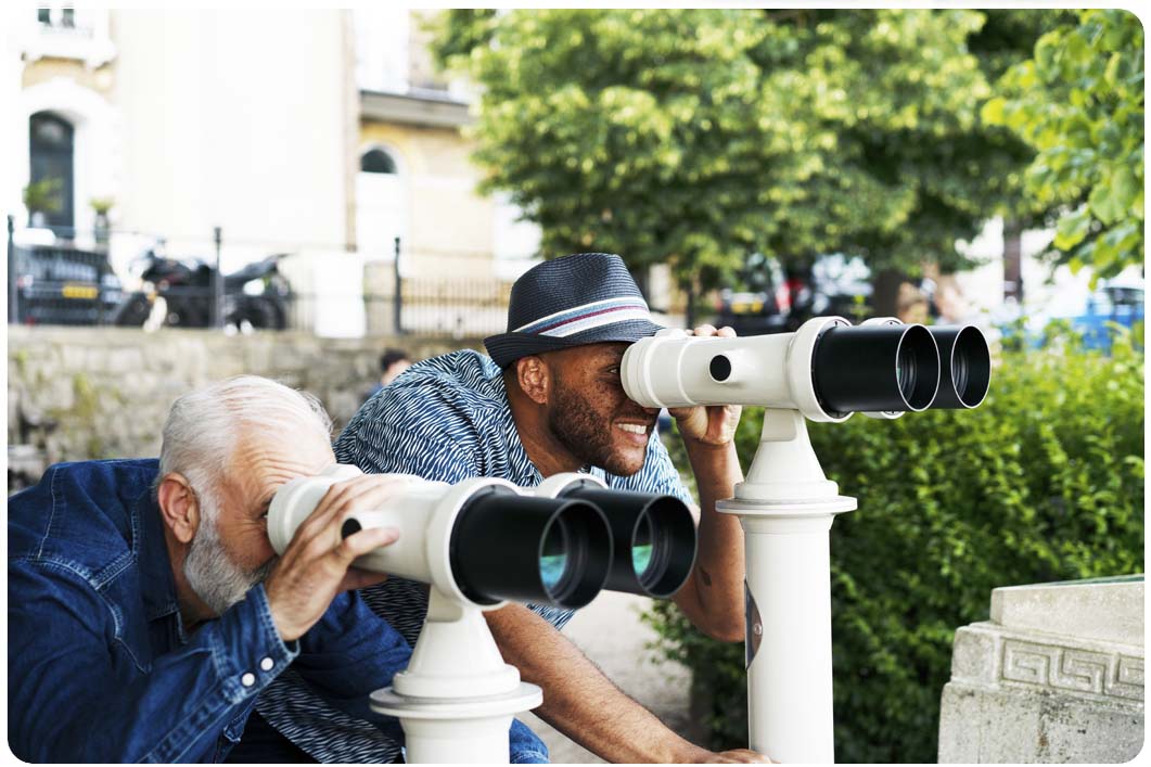 two men looking through seaside binoculars