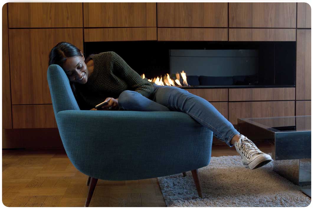 Woman relaxing using phone by the fireplace