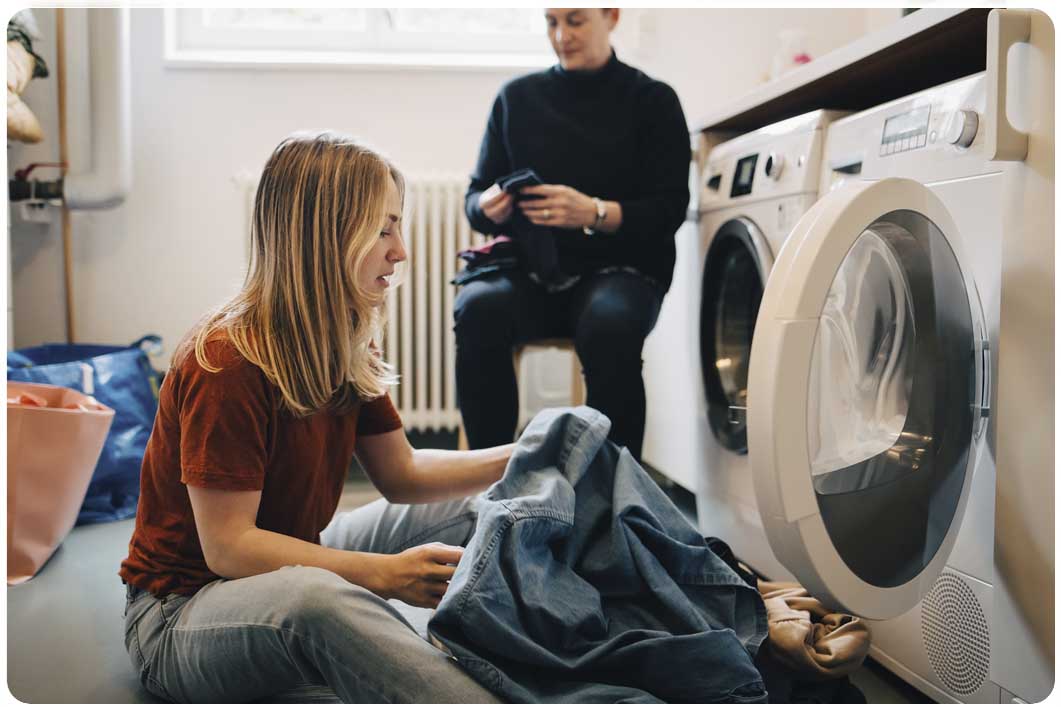 Person sitting on the floor next to a washing machine