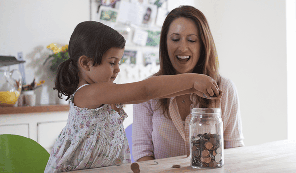 Mother and daughter putting coins in a jar