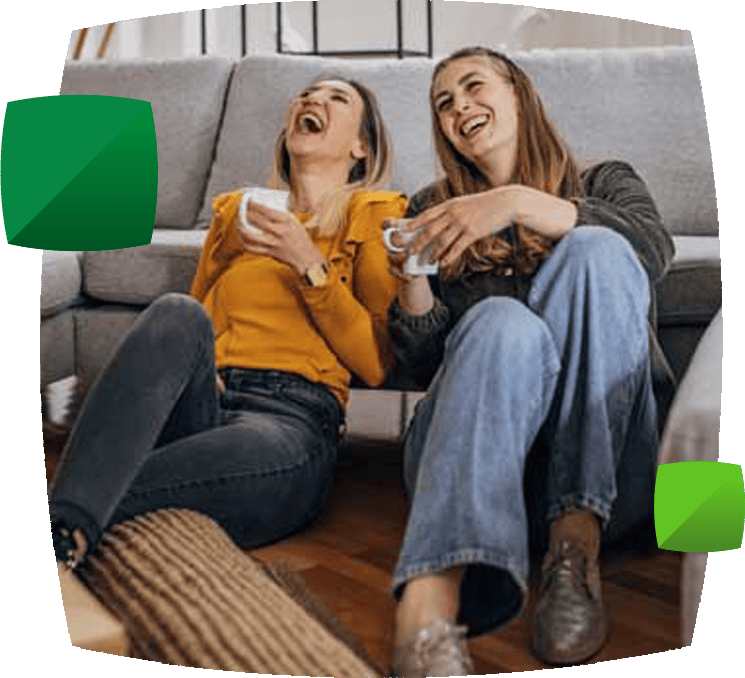 two woman laughing near sofa with boxes