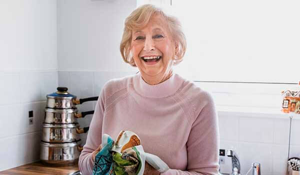 happy elderly lady washing dishes