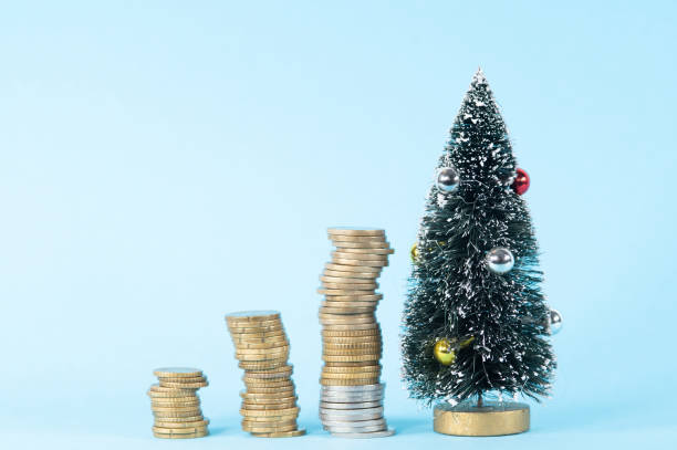 Piles of coins alongside a Christmas tree 