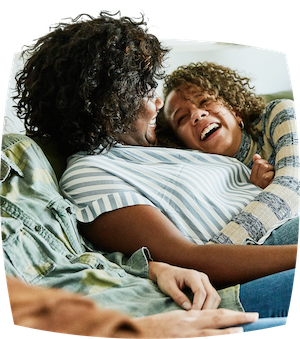 Mother and daughter smiling and hugging on a sofa.